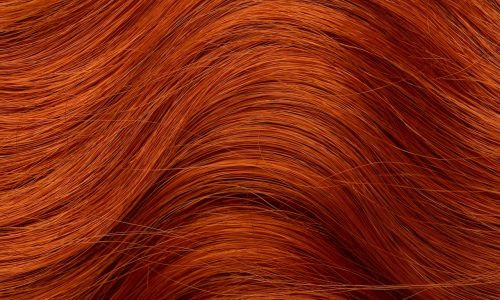 Red curly long hair close-up. A wave of hair as a background